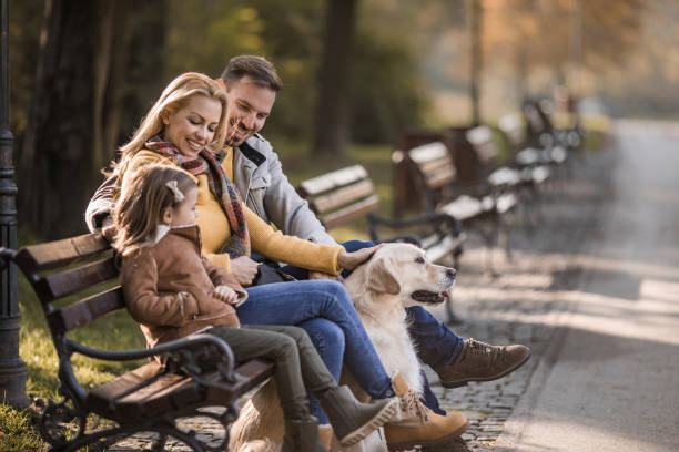 istock Happy family relaxing on a park bench while spending a day with their dog. 1036056602