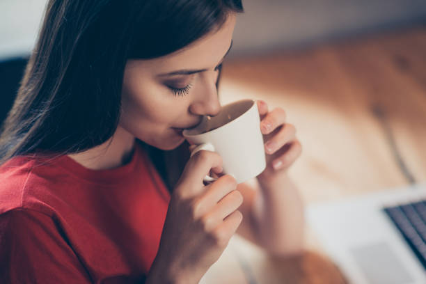 Crop photo of a girl who enjoys delicious aroma coffee with from Crop photo of a girl who enjoys delicious aroma coffee with from a white mug sitting in a cafe arabica coffee drink photos stock pictures, royalty-free photos & images