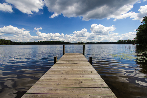 Northern Michigan lake in panoramic orientation with long wooden dock extending into lake.