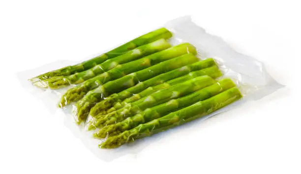 Photo of Asparagus vacuum sealed ready for sous vide cooking on white