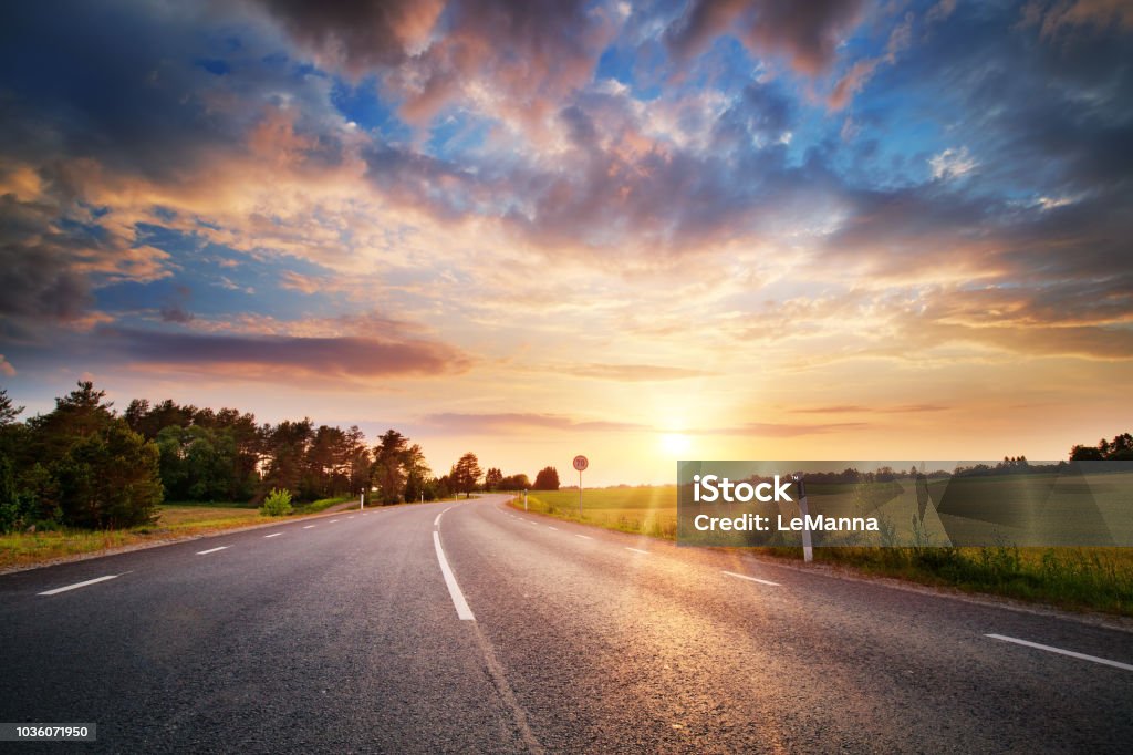 Strada asfaltata e linee divisorie al tramonto - Foto stock royalty-free di Strada