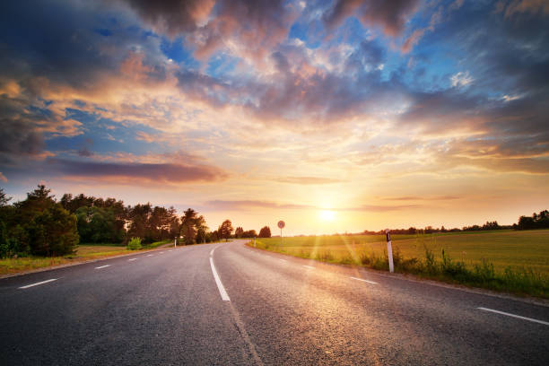 asphalt road and dividing lines at sunset - road landscape journey road trip imagens e fotografias de stock