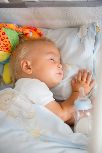istock Cute little baby boy, sleeping with bottle with formula milk 1036074990