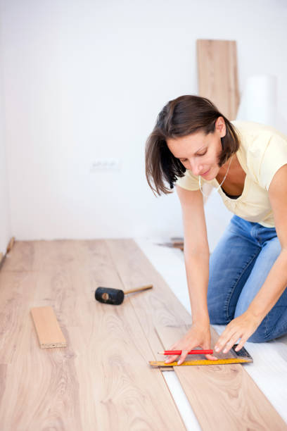 istock Happy young woman measuring and marking laminate floor tile 1036076180