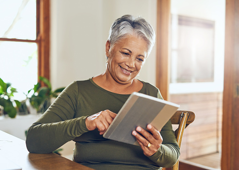 Shot of a mature woman using a digital tablet at home