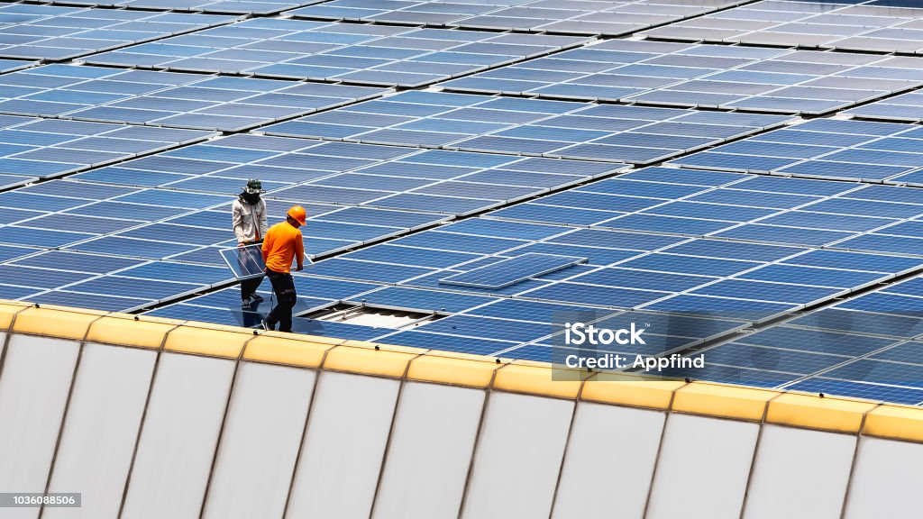 Solar power station. A Technician installing a solar panels on the factory roof. Solar Energy Stock Photo