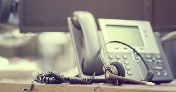 istock close up focus on call center headset device at telephone VOIP system at office desk for hotline telemarketing concept with vintage color filter 1036092486