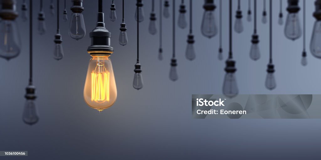 Glowing Light Bulb Standing Out From the Crowd Glowing Light Bulb between the others on dark background. Can be used leadership, innovation and individuality concepts.  (3d render) Light Bulb Stock Photo