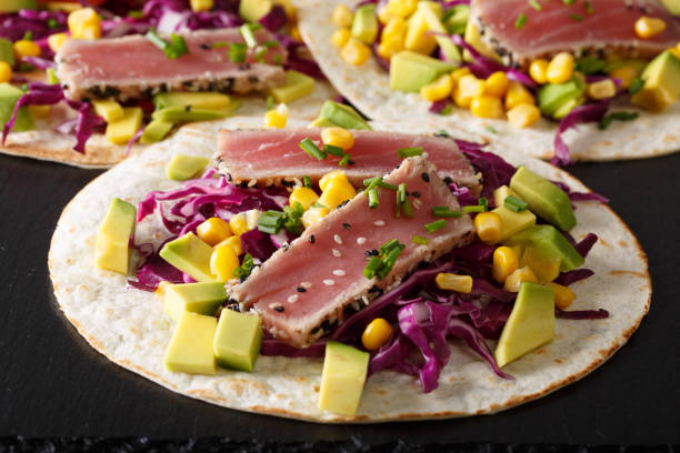 istock Mexican tacos with tuna, red cabbage, corn, avocado and onions close-up. horizontal 1036109700