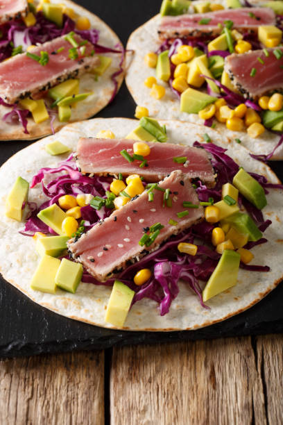 istock Mexican tortilla with tuna, red cabbage, corn, avocado and onions closeup. vertical 1036111972