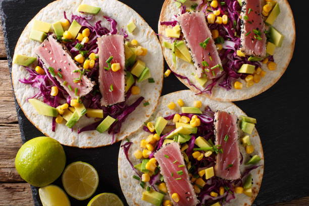 istock Mexican tacos with tuna, red cabbage, corn, avocado and onions close-up. horizontal top view 1036112096