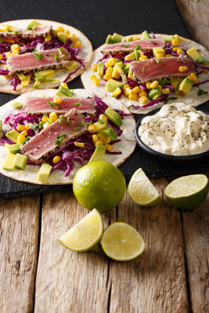 istock Appetizing food: tacos with tuna, sesame, corn, red cabbage and avocado close-up. vertical 1036112158