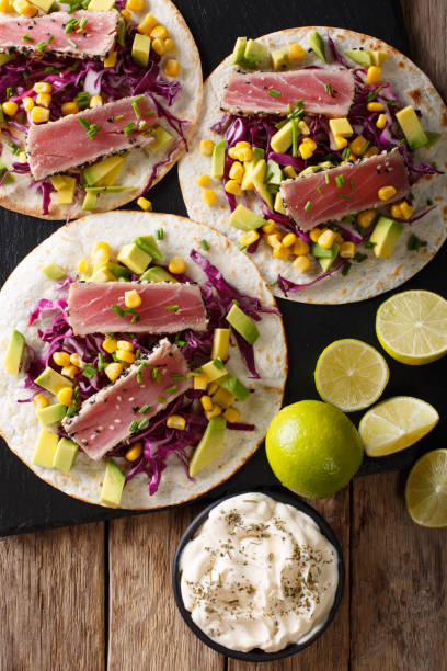 istock Mexican tacos with tuna, red cabbage, corn, avocado and onions close-up. Vertical top view 1036112992