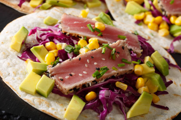 istock Fish tacos with tuna, red cabbage, corn, avocado and onions macro. horizontal 1036113058