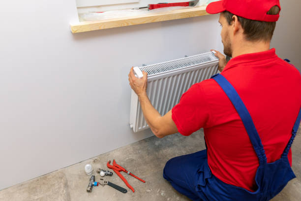 istock plumber installing heating radiator on the wall at home 1036126096