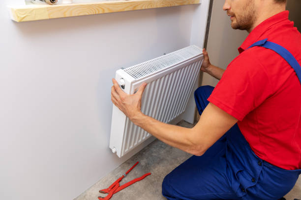 istock plumbing services - plumber installing heating radiator on the wall 1036126100