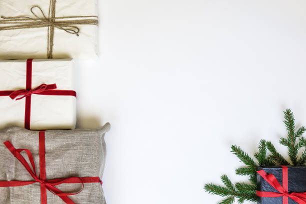 Christmas gift boxes on white background. Burlap canvas and organic white reused / recycled wrapping paper. Christmas gift boxes on white background. Burlap canvas and organic white reused / recycled wrapping paper. Red ribbon and natural linen string. Fir twig. Empty blank copy space for text. linen flax textile burlap stock pictures, royalty-free photos & images