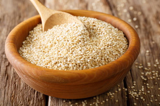 quinoa cruda de cerca en un tazón de madera. horizontal - quinoa spoon wood photography fotografías e imágenes de stock