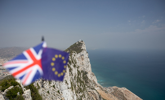 La Union Jack y bandera de la Unión Europea con el Peñón de Gibraltar, en el fondo, lo que indica la disputa sobre su soberanía y los efectos de Brexit con un montón de copyspace photo
