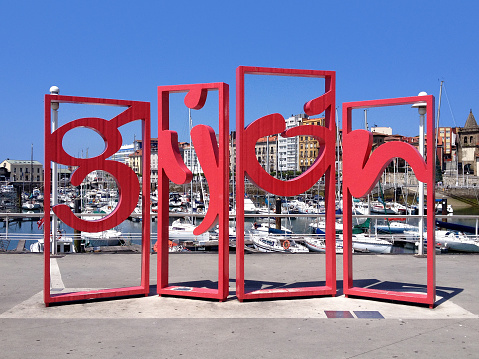 Dijon, Spain - July 3, 2014: Las Letronas is a giant reproduction of the touristic city brand located in the surroundings of the Jardines de la Reina. This sculpture, that forms the word Gijon with five letters of steel of 3 meters high and 25 cm width and more than 2 tons in weight was donated by the metal business federation of the asturias principate.