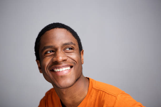 istock happy african man smiling and looking up against gray background 1036189946