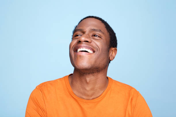 Close up african american man laughing against blue background