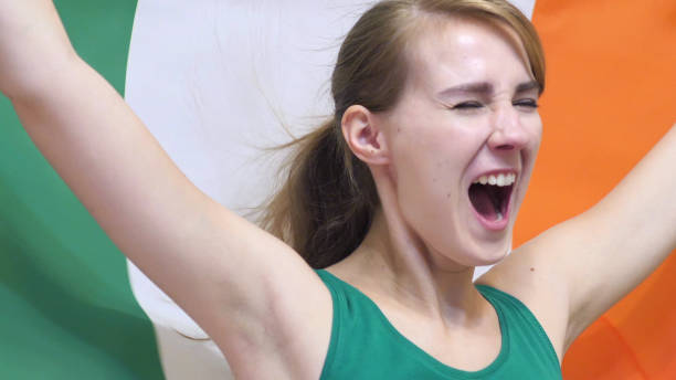 Irish Young Woman Celebrates holding the Flag of Ireland in Slow Motion Irish Young Woman Celebrates holding the Flag of Ireland in Slow Motion 15495 stock pictures, royalty-free photos & images