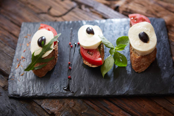 istock Italian bruschetta with chopped tomatoes, basil, mozzarella cheese and balsamic vinegar. Fresh homemade caprese bruschetta or crostini over black stone background, copy space 1036194094