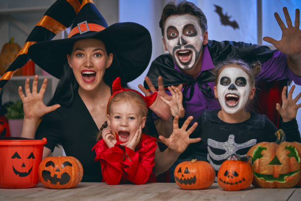 family celebrating Halloween Mother, father and their kids having fun at home. Happy family celebrating Halloween. People wearing carnival costumes and makeup. halloween face paint stock pictures, royalty-free photos & images