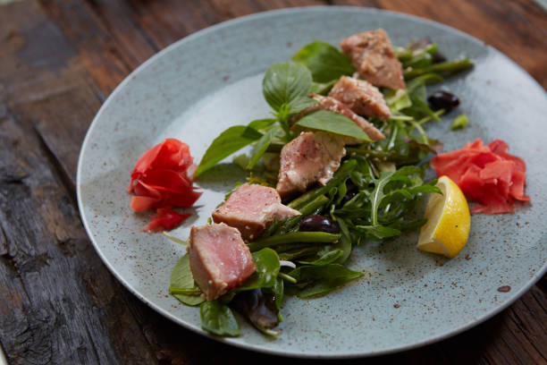 belle cuisine : thon steak au sésame, citron vert et salade fraîche gros plan sur une plaque sur la table. - tuna steak grilled tuna food photos et images de collection
