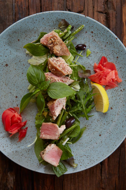 hermosa comida: atún filete en close-up en la ensalada en un plato sobre la mesa, limón y sésamo. - tuna steak fillet food plate fotografías e imágenes de stock