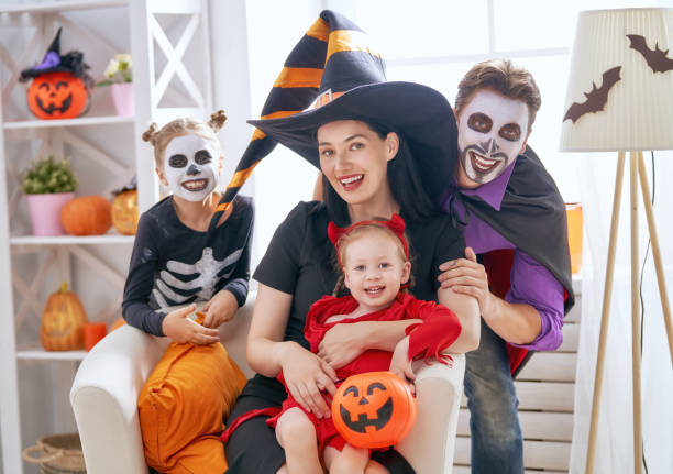 family celebrating Halloween Mother, father and their kids having fun at home. Happy family celebrating Halloween. People wearing carnival costumes and makeup. face paint halloween adult men stock pictures, royalty-free photos & images