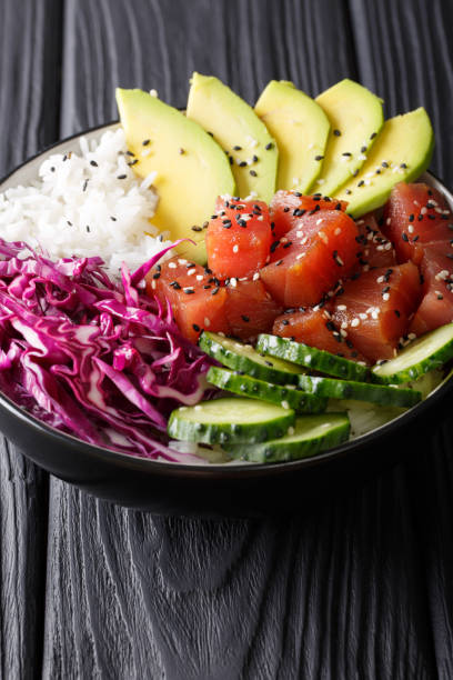 istock Tuna poke bowl with rice, cucumber, red cabbage and avocado close-up. vertical 1036201430