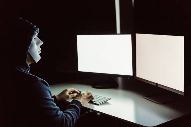 istock Anonymous and masked hacker using computer with isolated white monitor screen to insert any text, word, pictures - online cyber crime concept. 1036209564