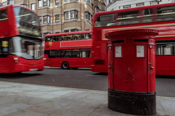 three blurred red busses passing by in the street of London