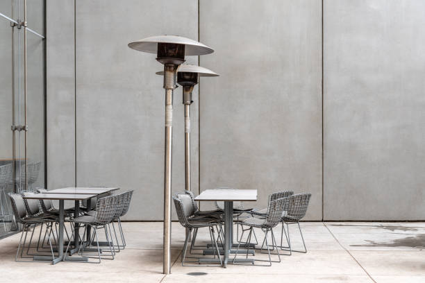 Modern restaurant terrace with tables, chairs and heaters against concrete wall with space for copy with no people. New York City, USA
