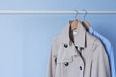 Women's trench coat and shirt on a wooden hanger
