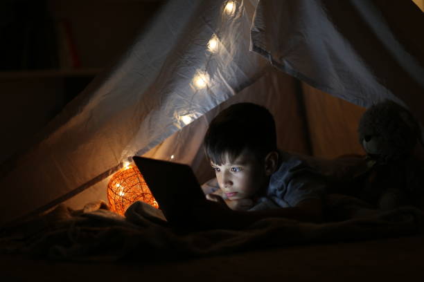 istock Little boy reading book on digital tablet at night 1036231814