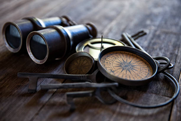 This is a close up photograph of a Antique Compasses Keys and Binoculars on Old Wood