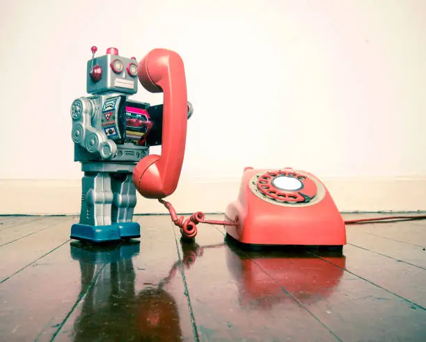 big silver robot toy on the phone standing on an old wooden floor toned image