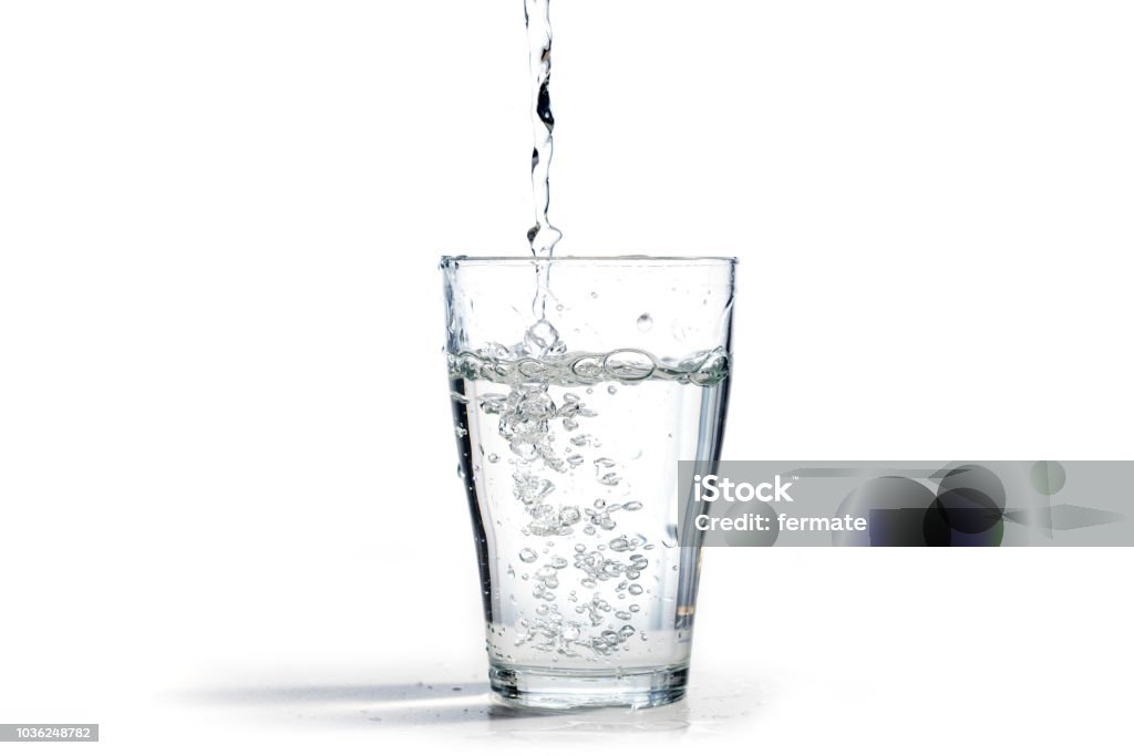 water is poured into a drinking glass, isolated on a white background with copy space Water Stock Photo