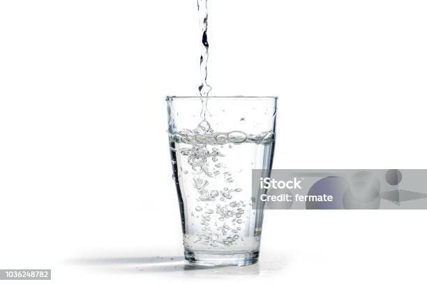Water Is Poured Into A Drinking Glass Isolated On A White Background With Copy Space Stock Photo - Download Image Now
