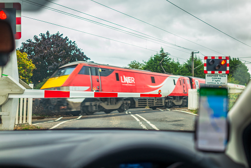 East Lothian, UK - A view from a car of a high-speed train, operated by LNER as it travels past a level crossing on the East Coast Mainline.