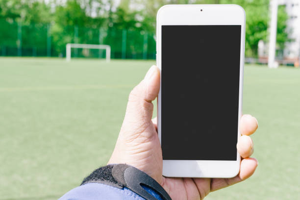 istock Cropped Hand Holding Mobile Phone Over Field 1036252474
