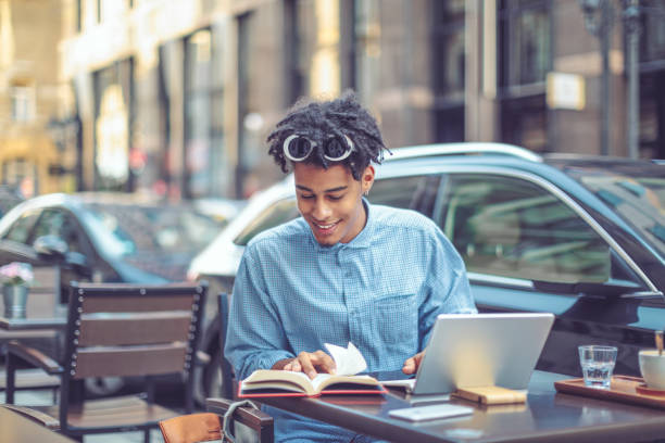istock Young student is flipping up a book in a sidewalk caffee 1036256660