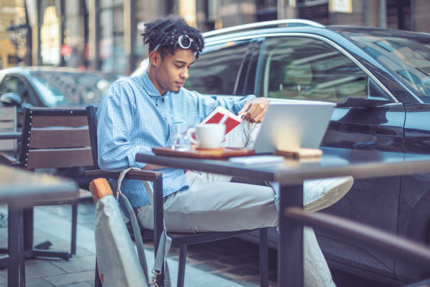 istock Young student is flipping up a book in a sidewalk caffee 1036256860