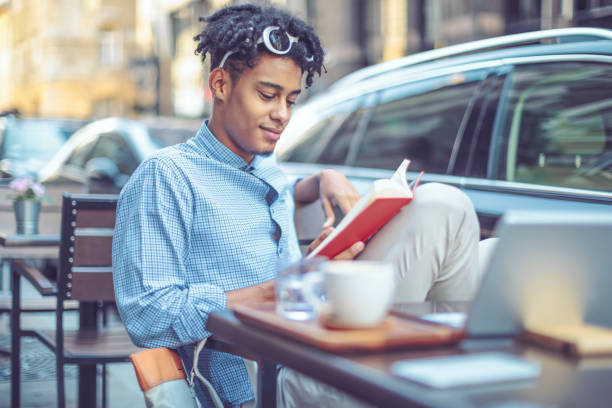 istock Young student is flipping up a book in a sidewalk caffee 1036257518