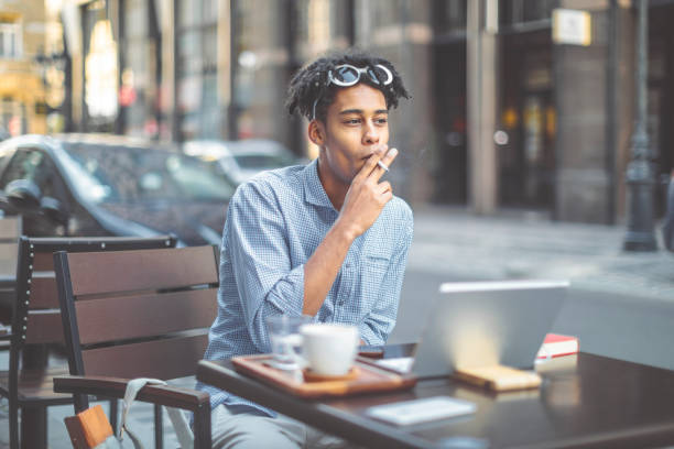 istock Hipster is smoking a cigarette in a sidewalk cafe 1036259188