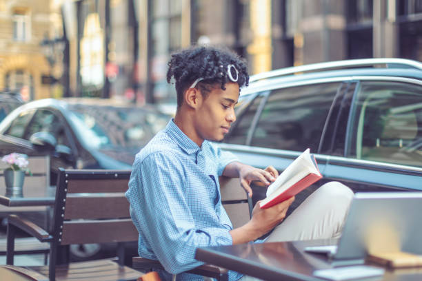 istock Young student is flipping up a book in a sidewalk caffee 1036259876
