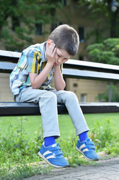 istock sad child boy sitting on a bench 1036260130